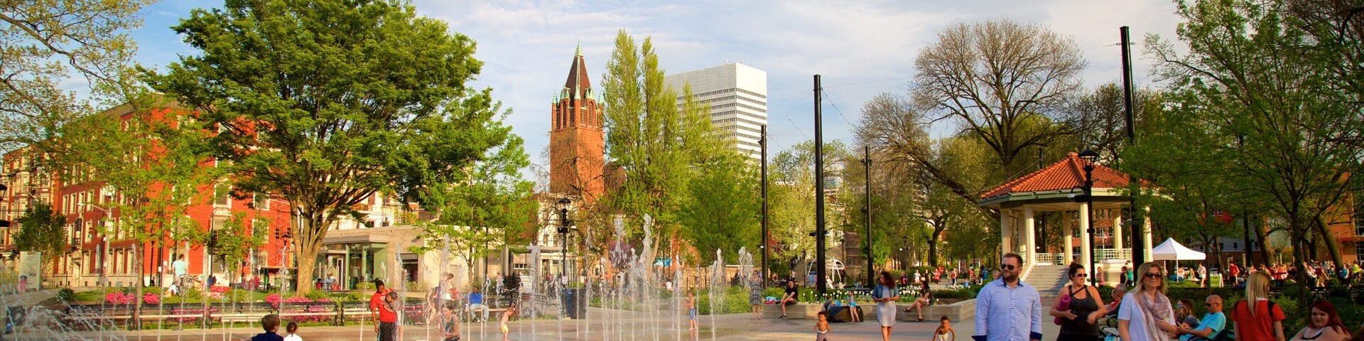 Una plaza pública con una fuente de agua, árboles y un quiosco.