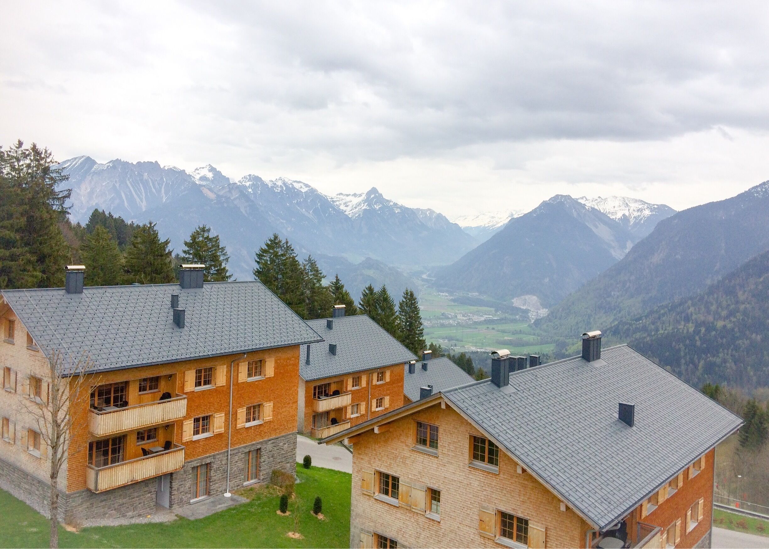 A mountain lodge with a view of snow-capped peaks and a valley.