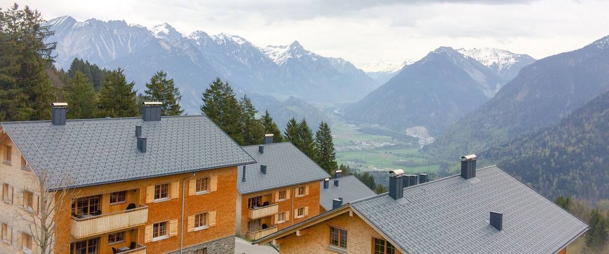 A mountain lodge with a view of snow-capped peaks and a valley.