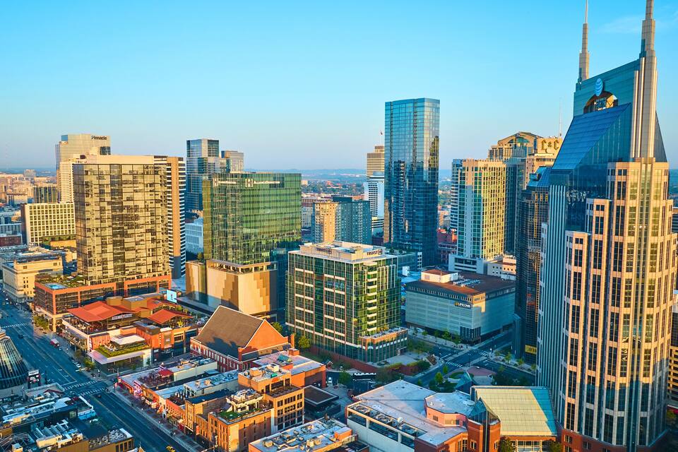 A cityscape with modern skyscrapers, a prominent tower with a spire, and a mix of commercial and residential buildings.