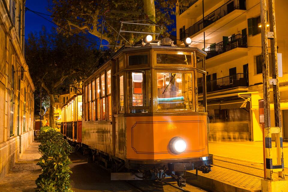 A vintage tram on a city street at night.