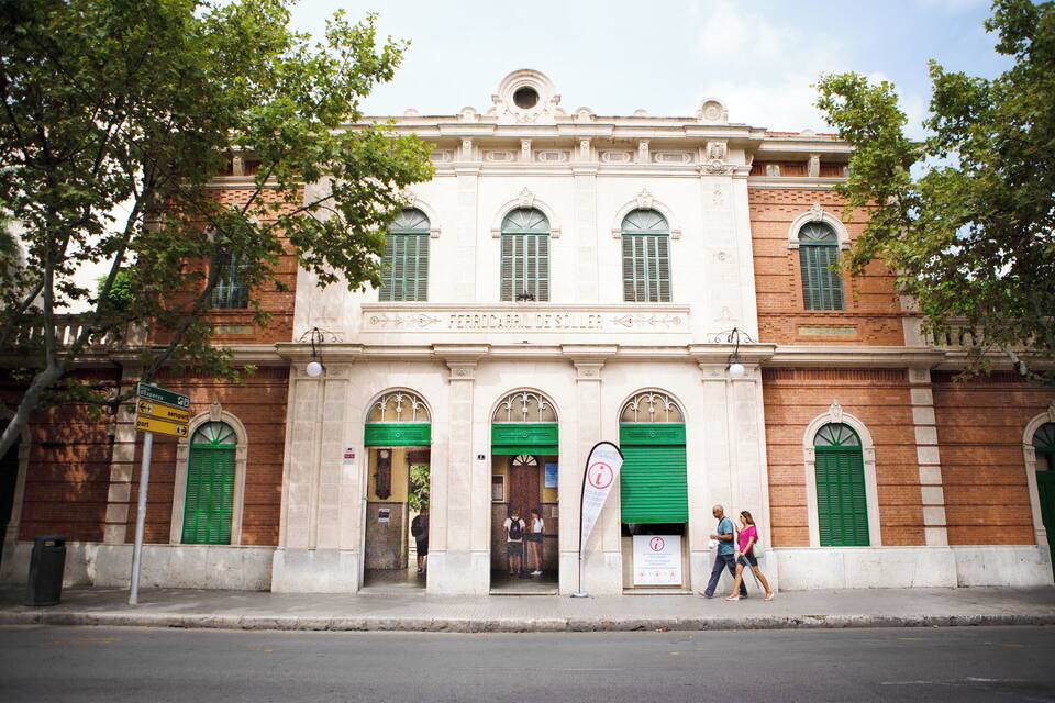 A historic building with green shutters and a sign reading "FERRDARRIL DE SOLLER".