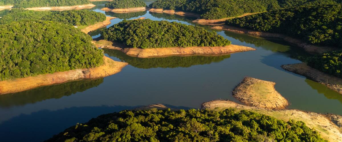 A river meandering through a dense forest with multiple islands and a clear sky.