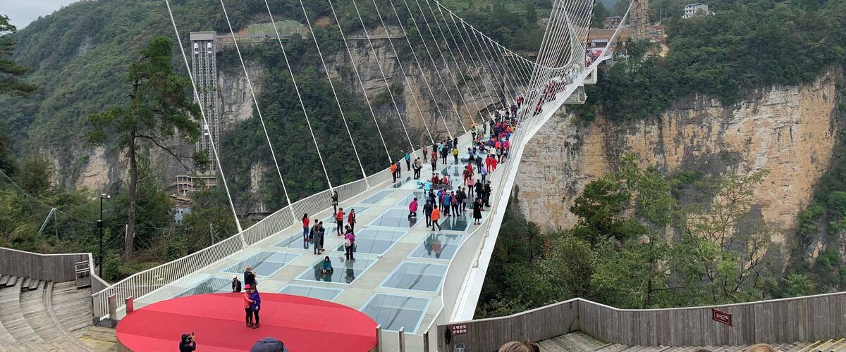 A suspension bridge with a glass walkway over a canyon.