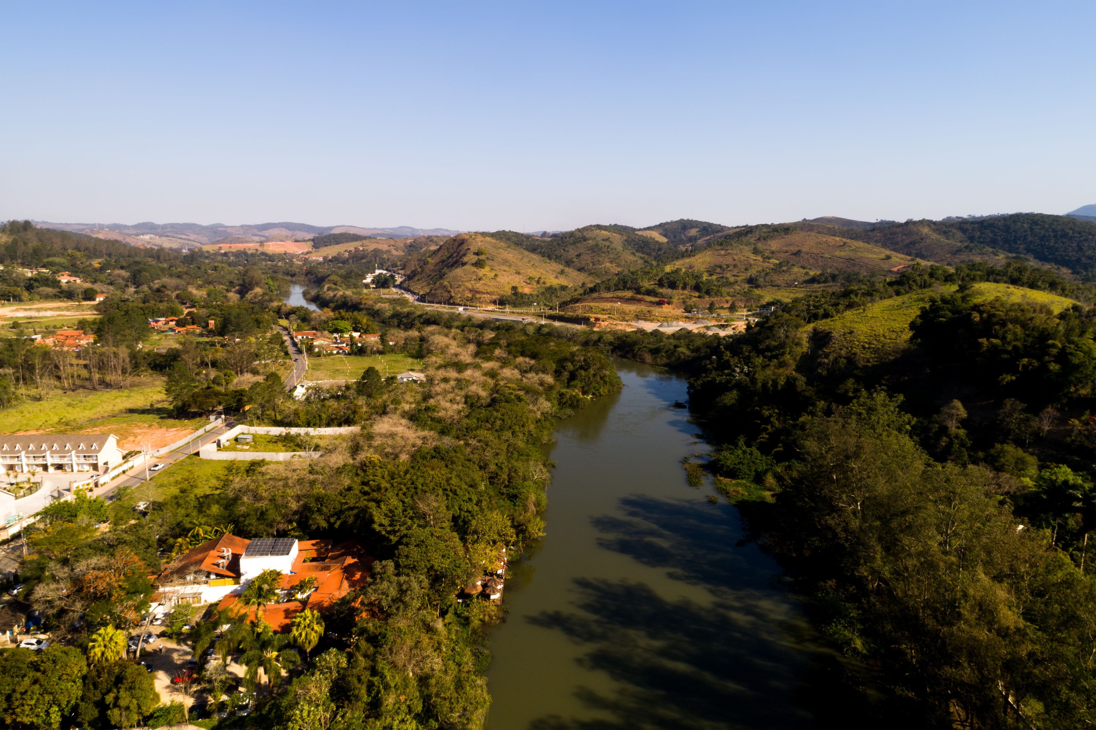 A river winding through a valley with hills and a small town with buildings and a bridge.