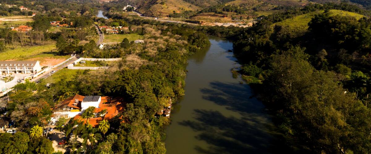 A river winding through a valley with hills and a small town with buildings and a bridge.