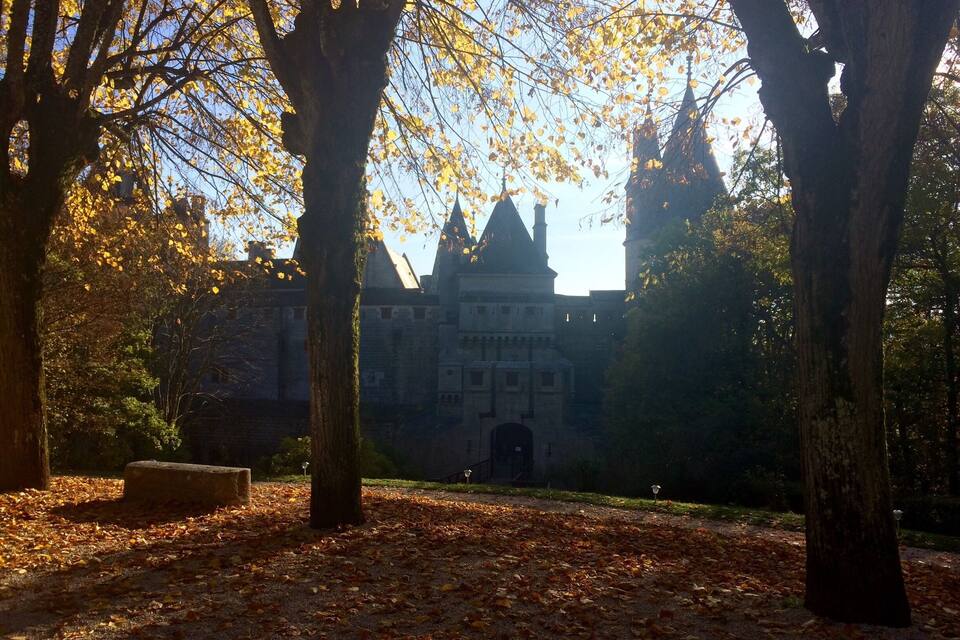 A park with trees and a historic building in the background.