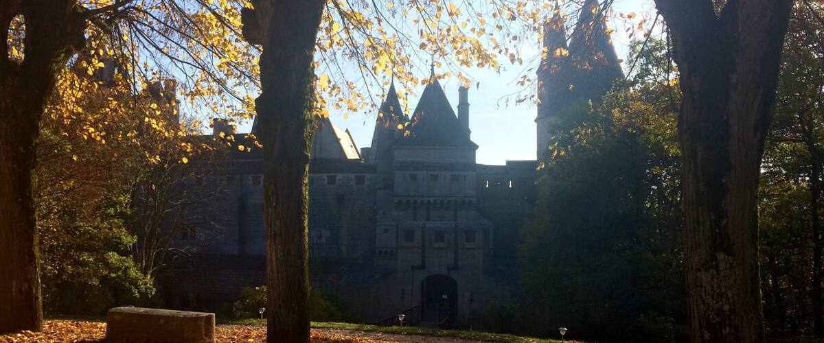 A park with trees and a historic building in the background.