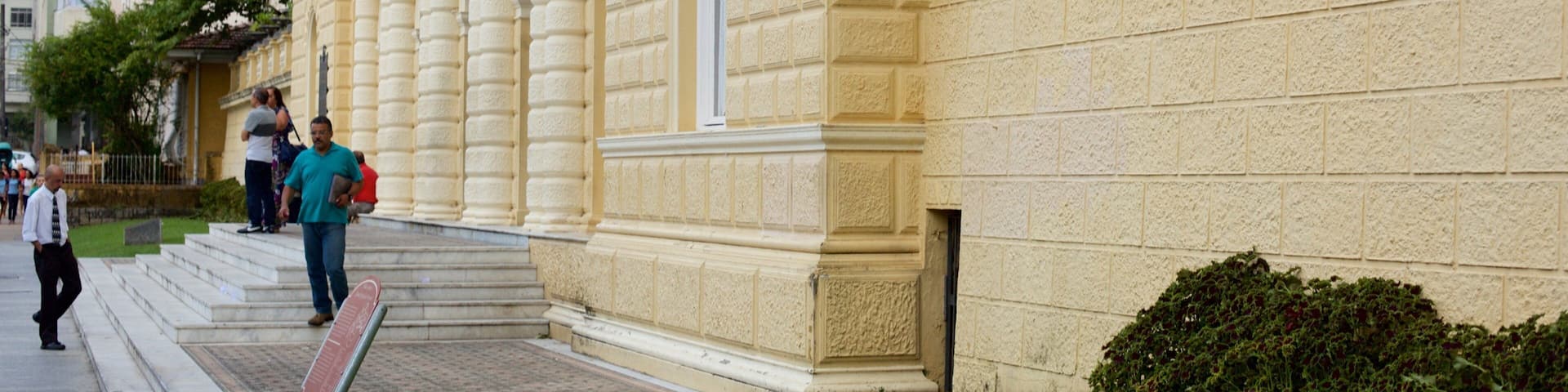 A historic building with classical architecture, a set of stairs, and a small garden.