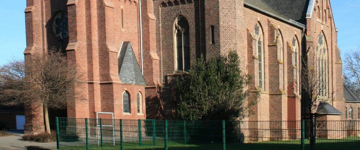 A red brick church with a tall tower and a pointed steeple.