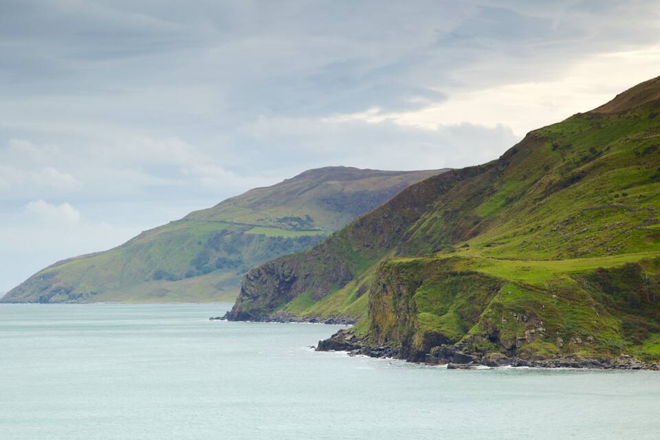 A coastal landscape with green hills and a calm sea.
