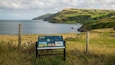 Ett kustlandskap med en skylt som berättar om Torr Head och Ballycastle.