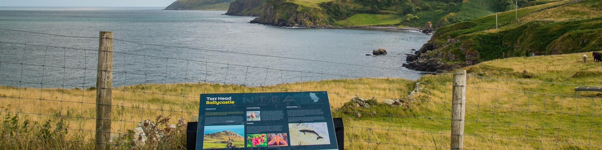 Paisagem costeira com uma placa indicativa sobre Torr Head, Ballycastle.