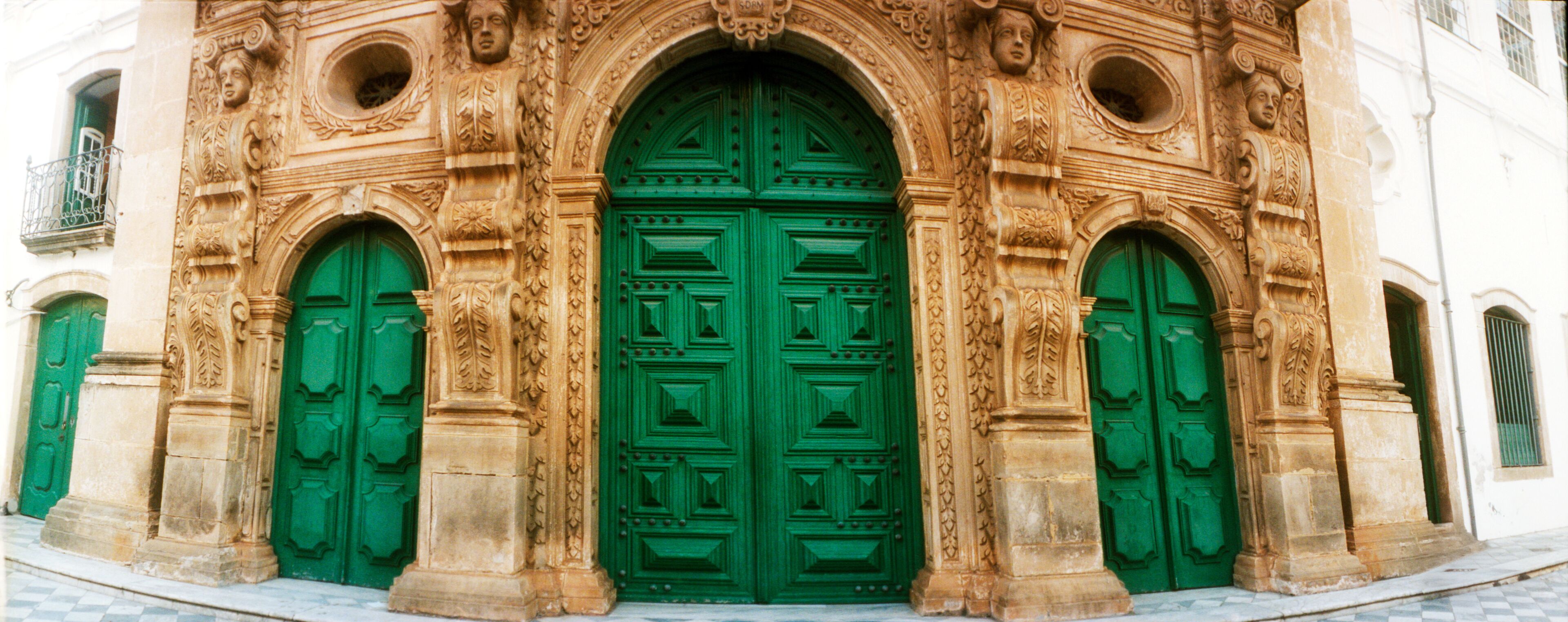 A building with ornate stone carvings and green doors.