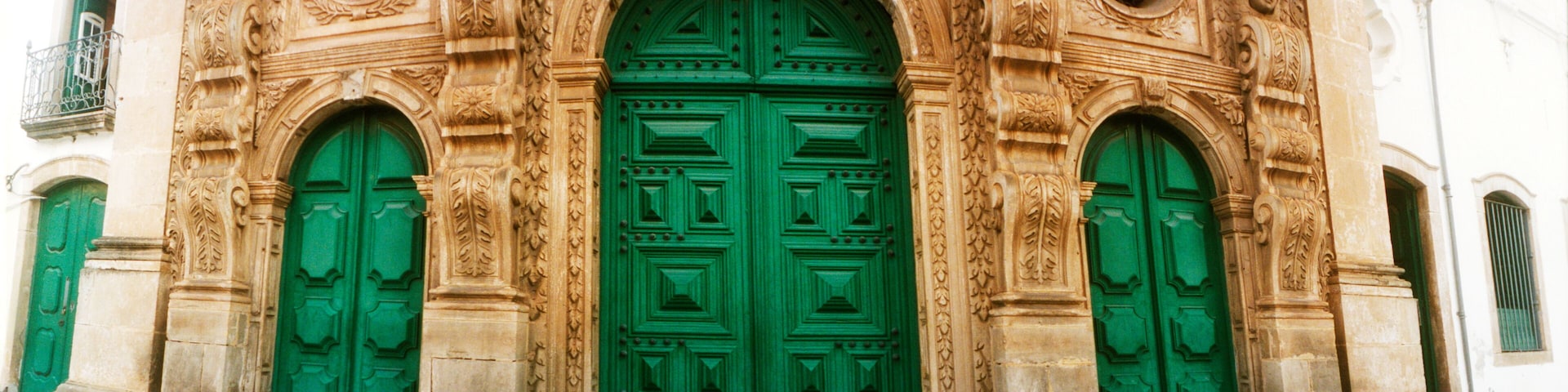 A building with ornate stone carvings and green doors.