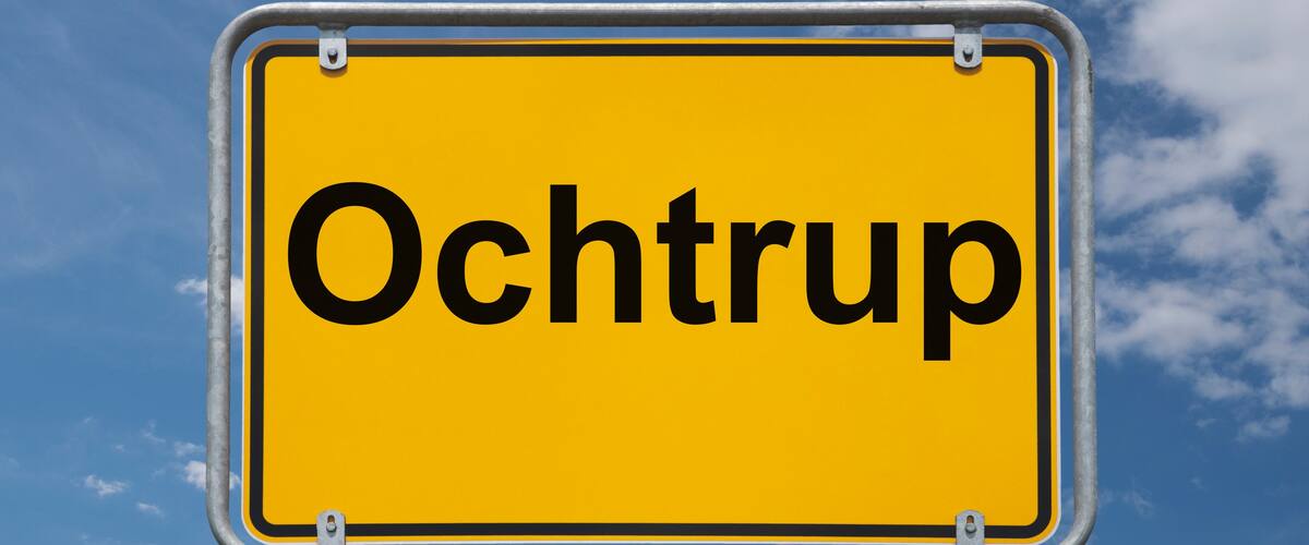 A yellow sign with the word "Ochtrup" against a blue sky with clouds.