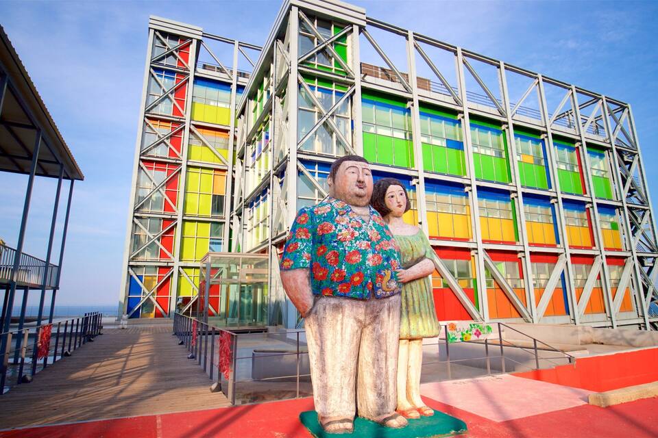 A colorful building with a metal framework and a statue of a man and woman in front.