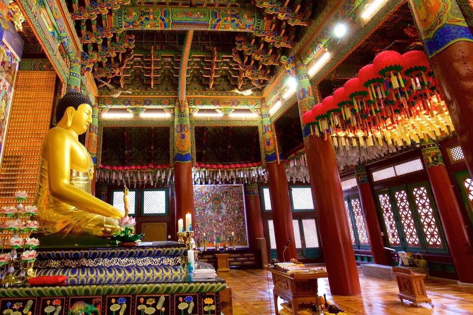 Una estàtua daurada de Buda en l'interior ricament decorat d'un temple.