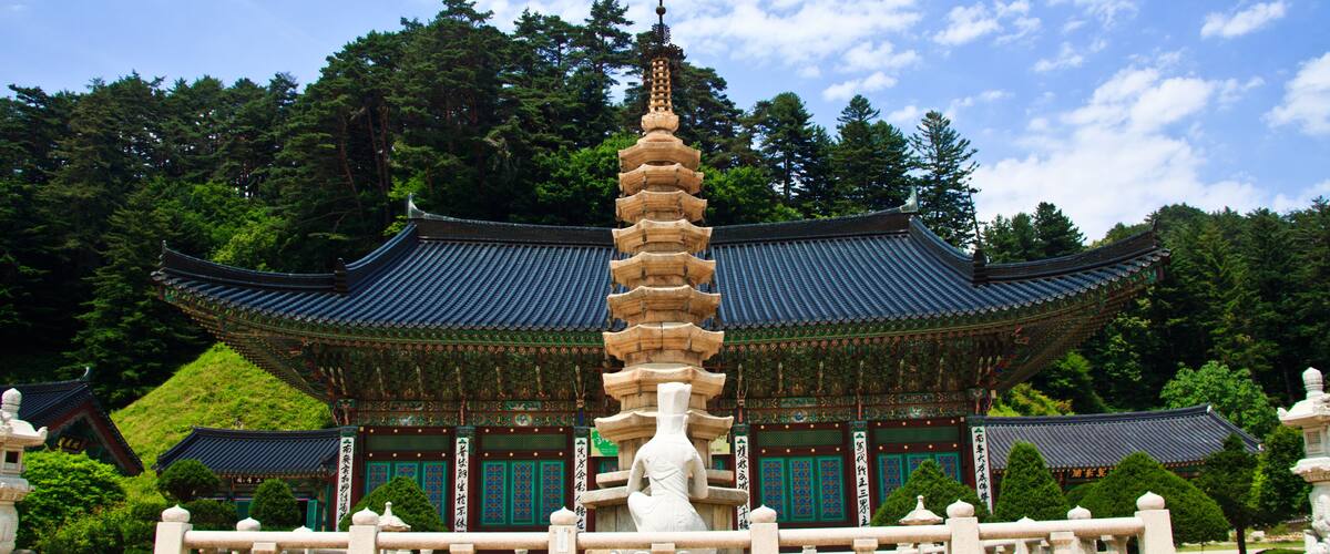 A pagoda-style building with a multi-tiered stone pagoda in front.