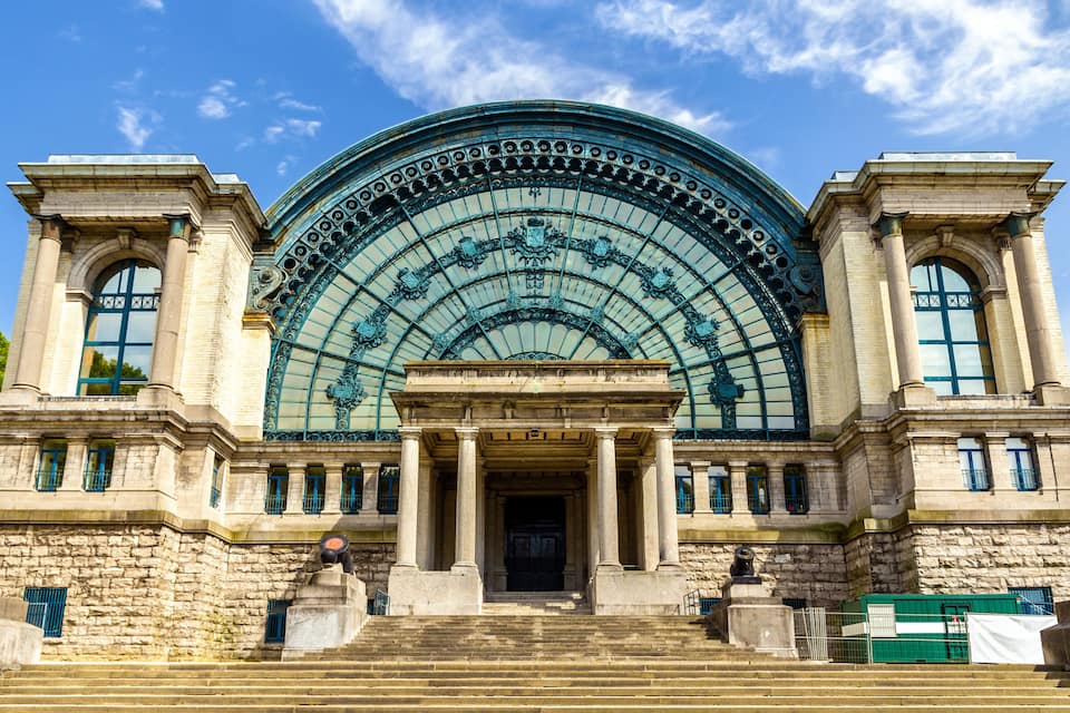 A grand building with a large arched glass facade and classical columns.