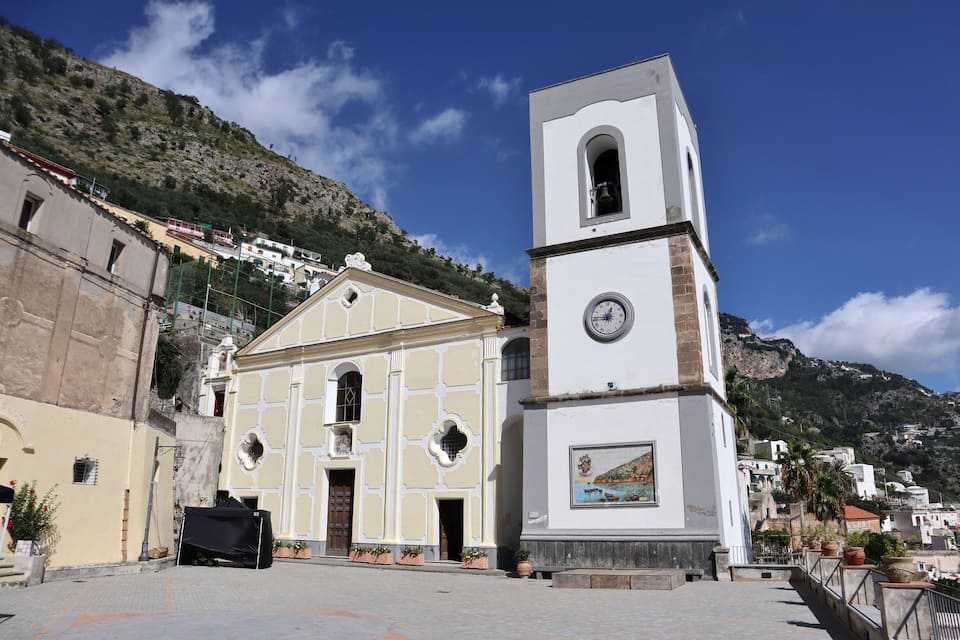 Uma igreja com um campanário e um mural, com montanhas ao fundo.