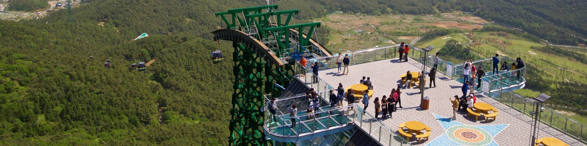 A cable car station overlooking a coastal city with a view of the sea and distant mountains.