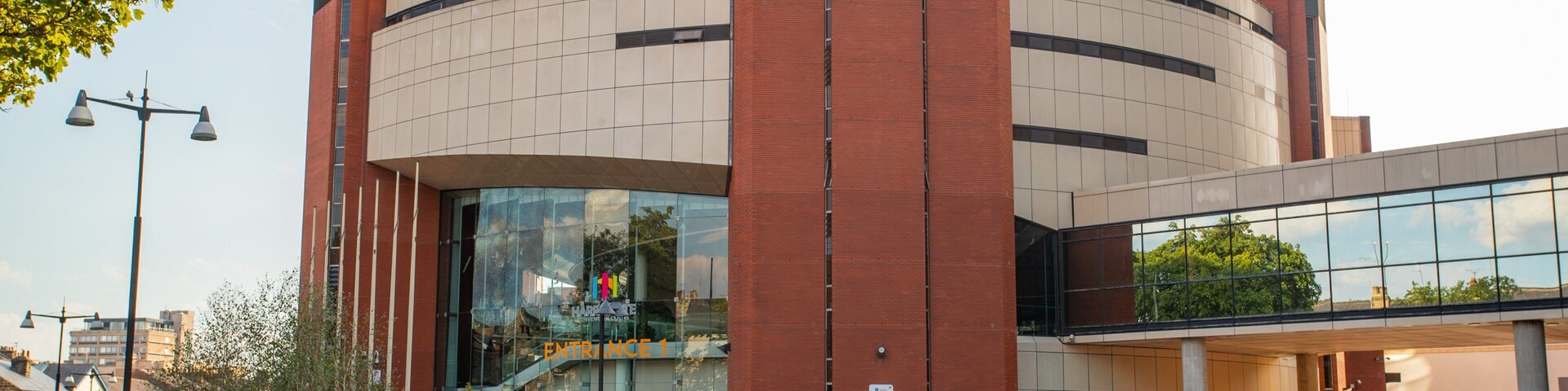 Un edificio moderno con fachada curva, amplias ventanas de vidrio y una entrada destacada.