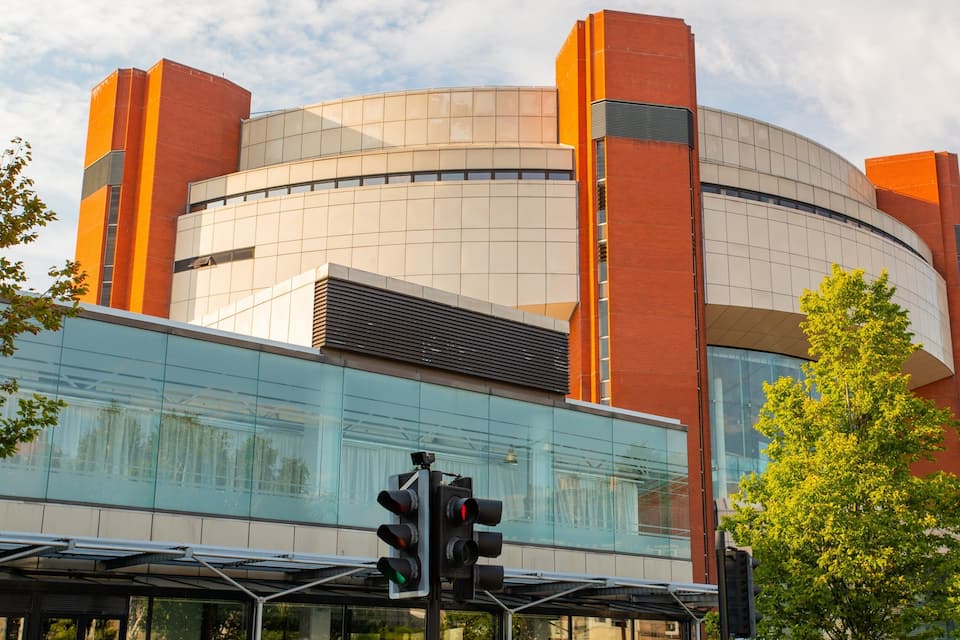 A modern building with a curved facade, large glass windows, and red brick accents.