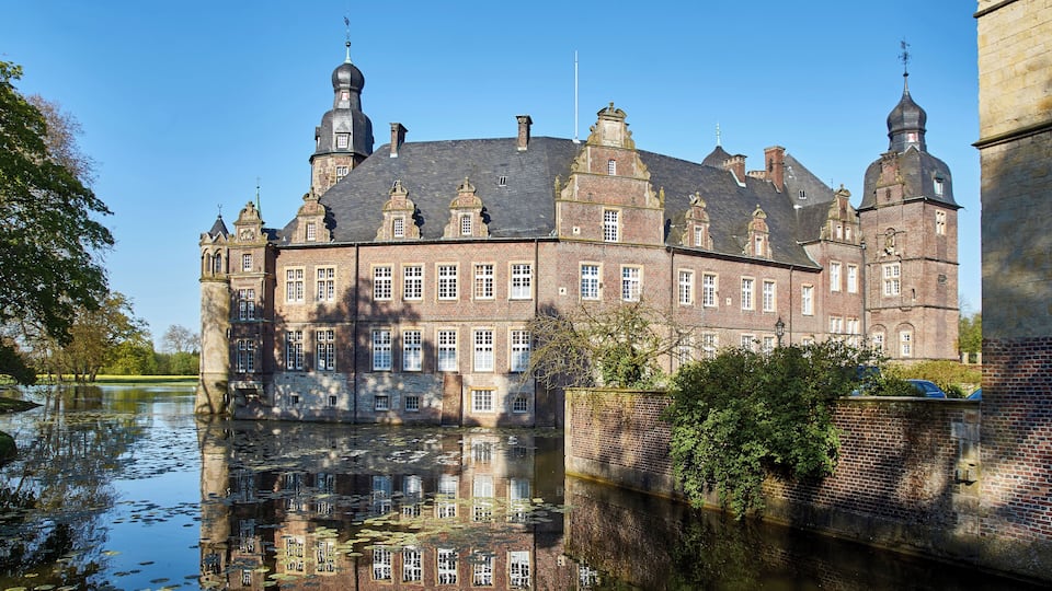 A historic brick building with multiple towers and a moat.