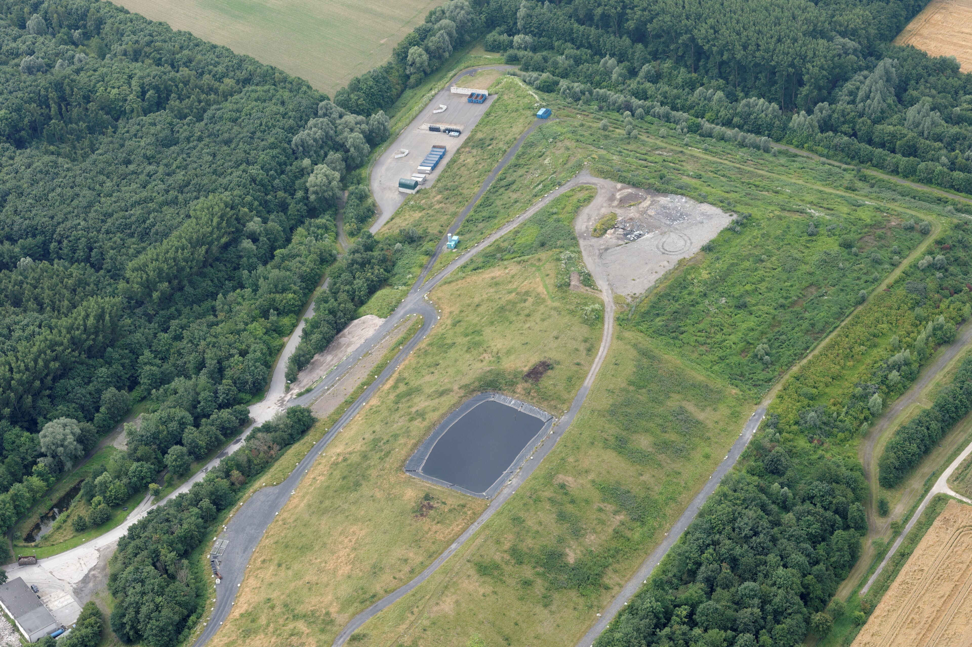 An aerial view of a rural area with a large open field, a pond, and a road network.