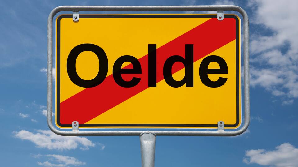 A road sign with the word "Oelde" against a blue sky with clouds.