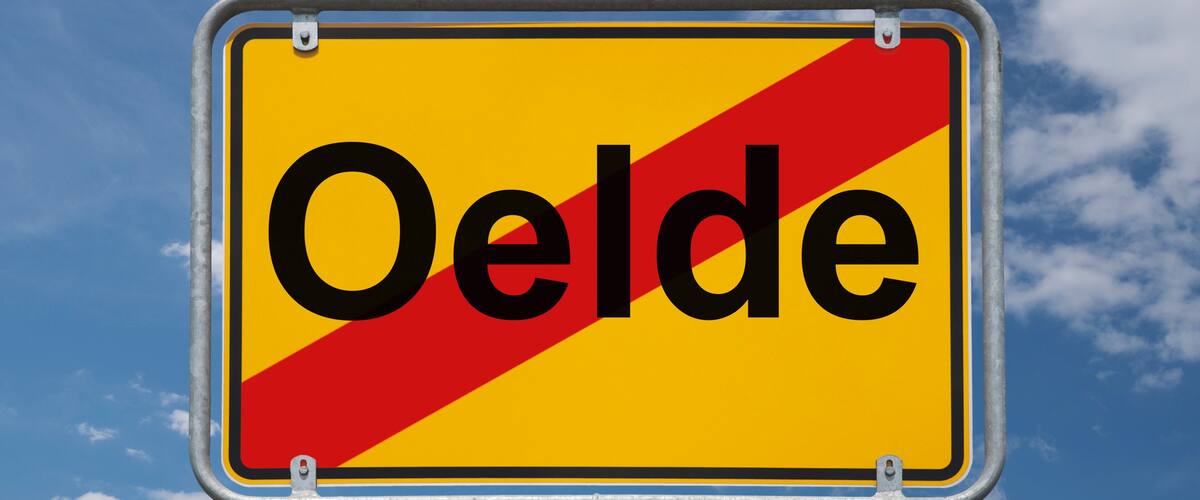A road sign with the word "Oelde" against a blue sky with clouds.