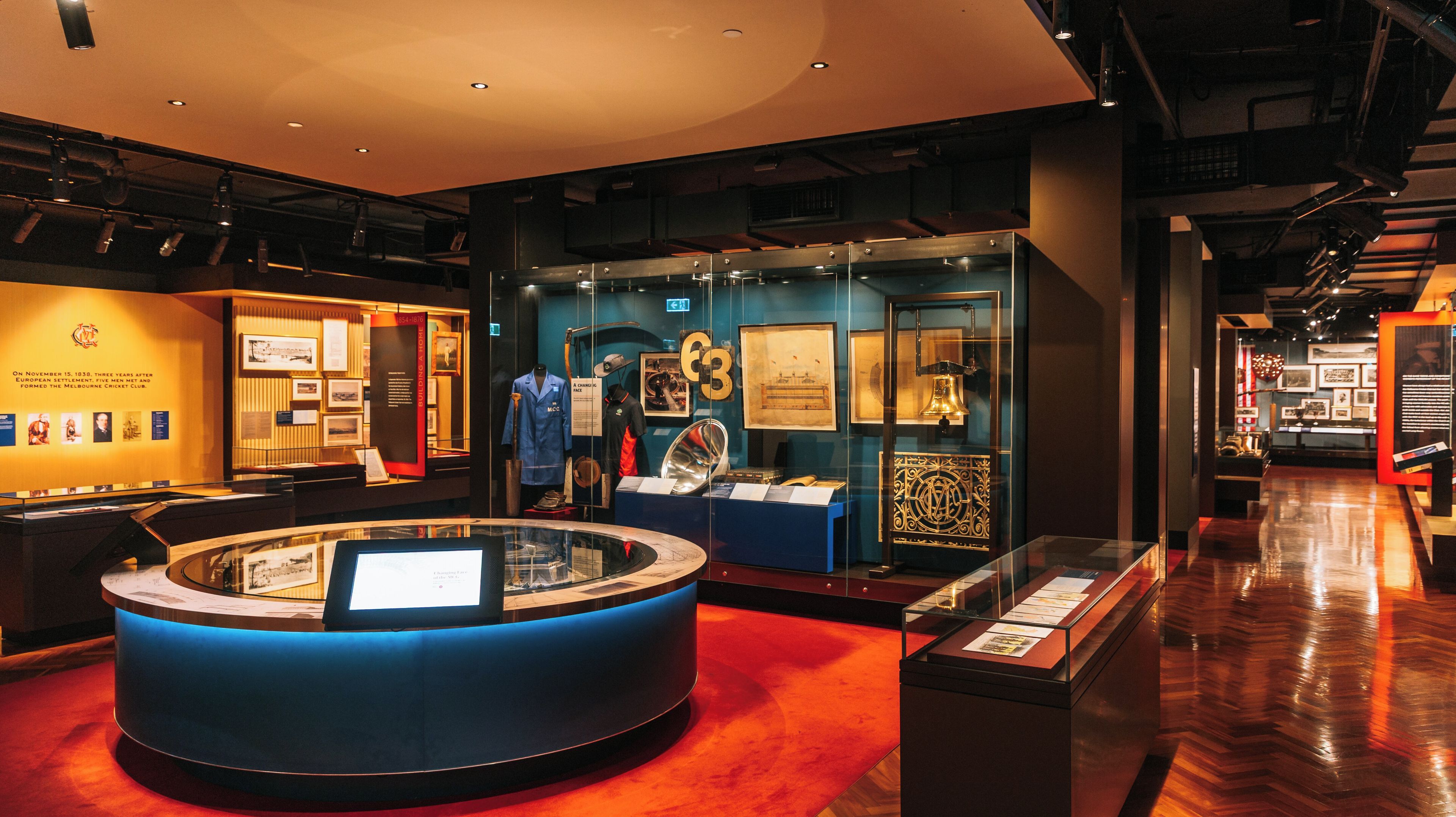 Una mostra museale con manufatti storici, tra cui una mazza da cricket, un cappotto blu e una campana.