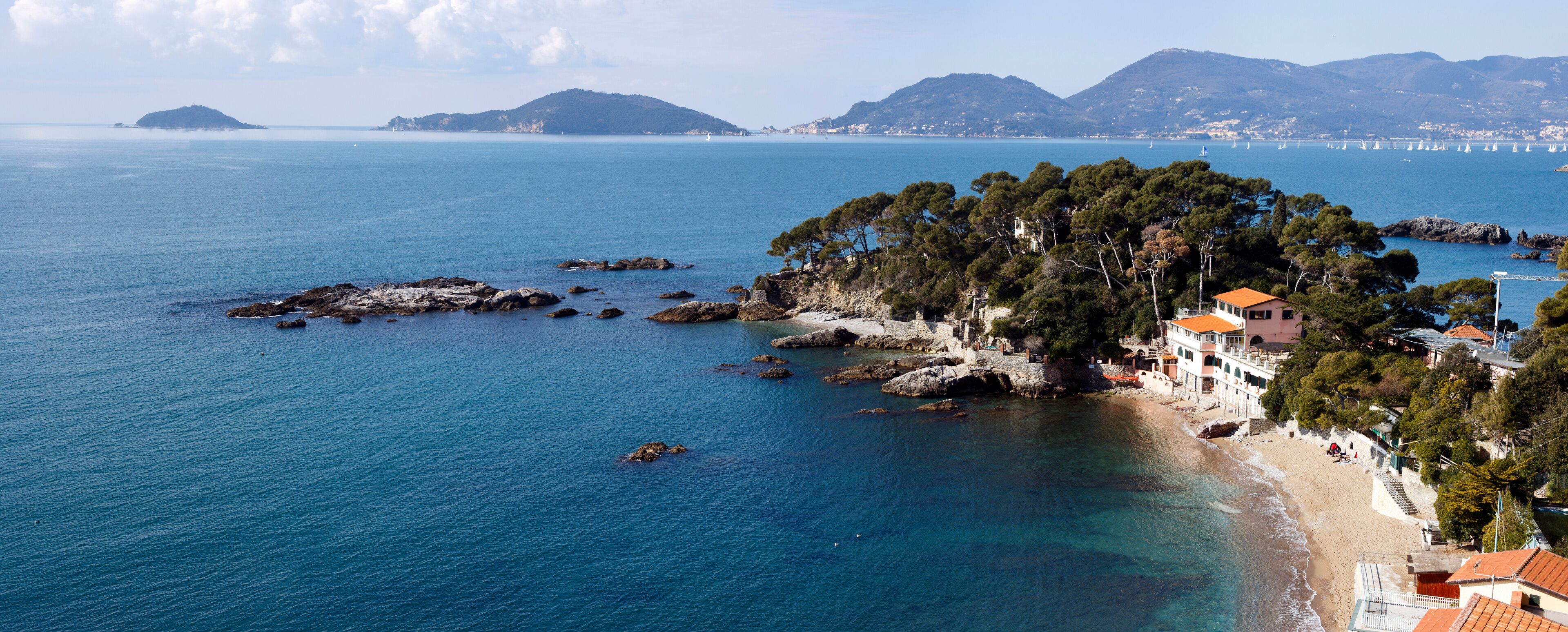 A coastal town with a beach, rocky outcrops, and a forested island.