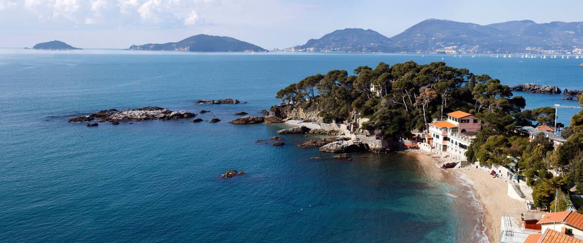 A coastal town with a beach, rocky outcrops, and a forested island.