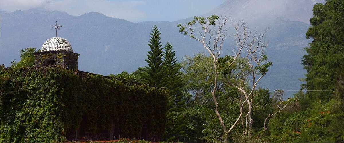 A mountain with a dome-shaped structure in the foreground and a volcano in the background.