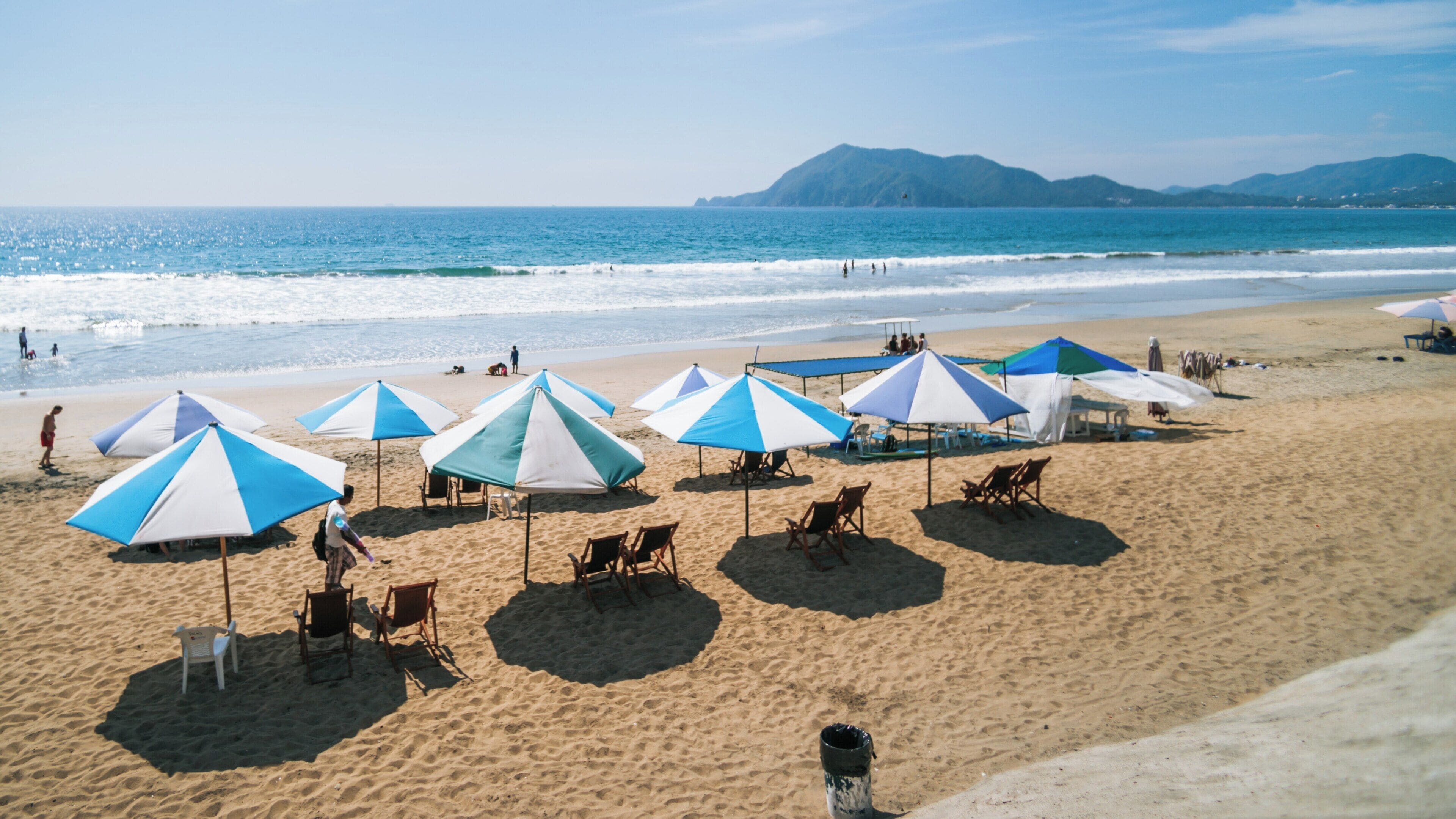 Enjoying sunny days at Oro Beach in Manzanillo, Colima, Mexico with shaded umbrellas and sandy shores