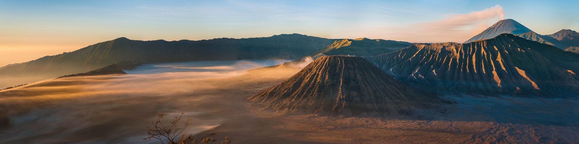 Cordillera montañosa con un pico destacado y un valle cubierto de niebla.
