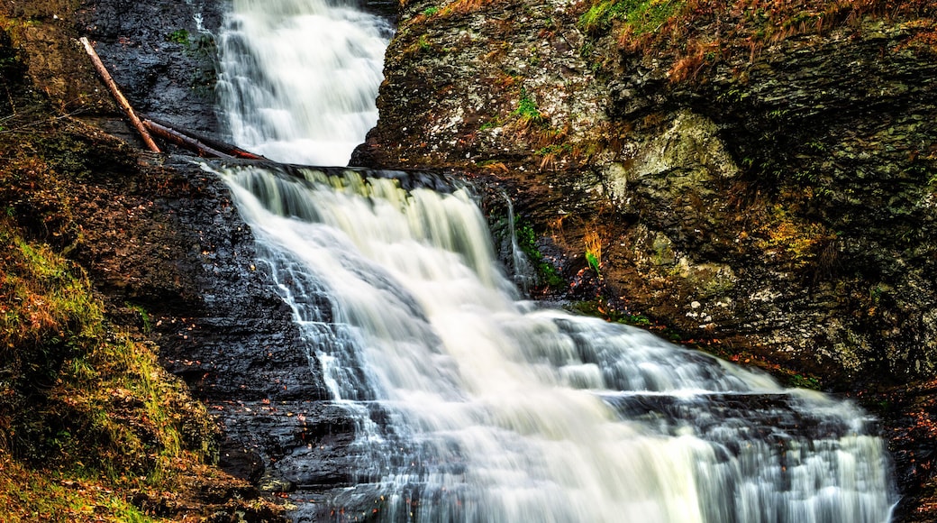 A multi-tiered waterfall surrounded by autumn foliage and a wooden viewing platform.