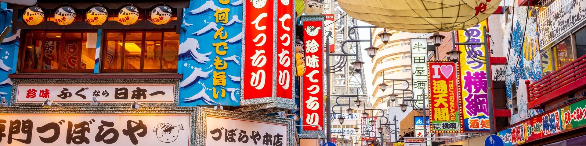 Uma rua movimentada com sinalização e lanternas tradicionais japonesas.