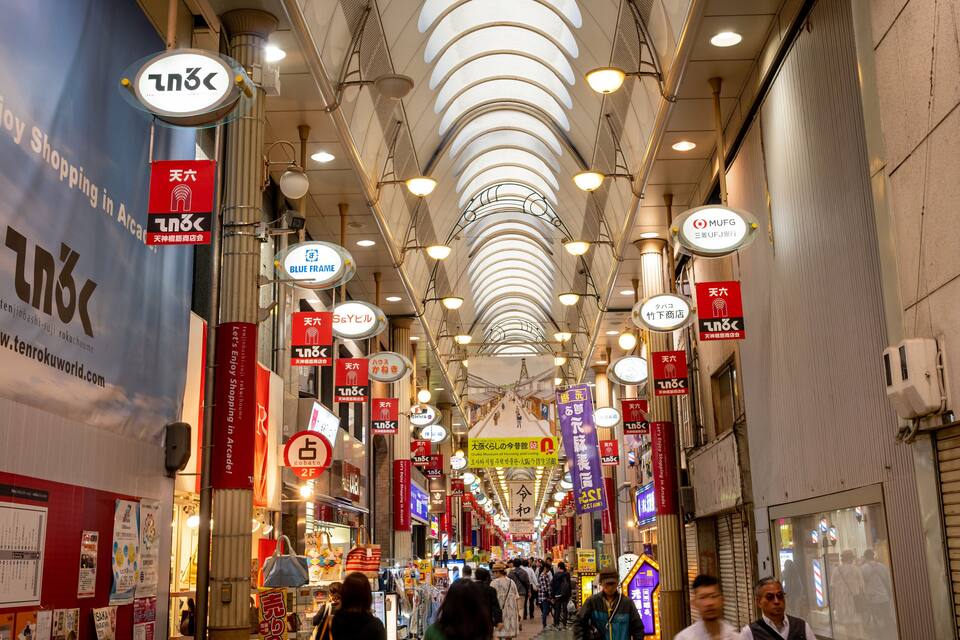 A busy indoor shopping arcade with numerous signs and advertisements.