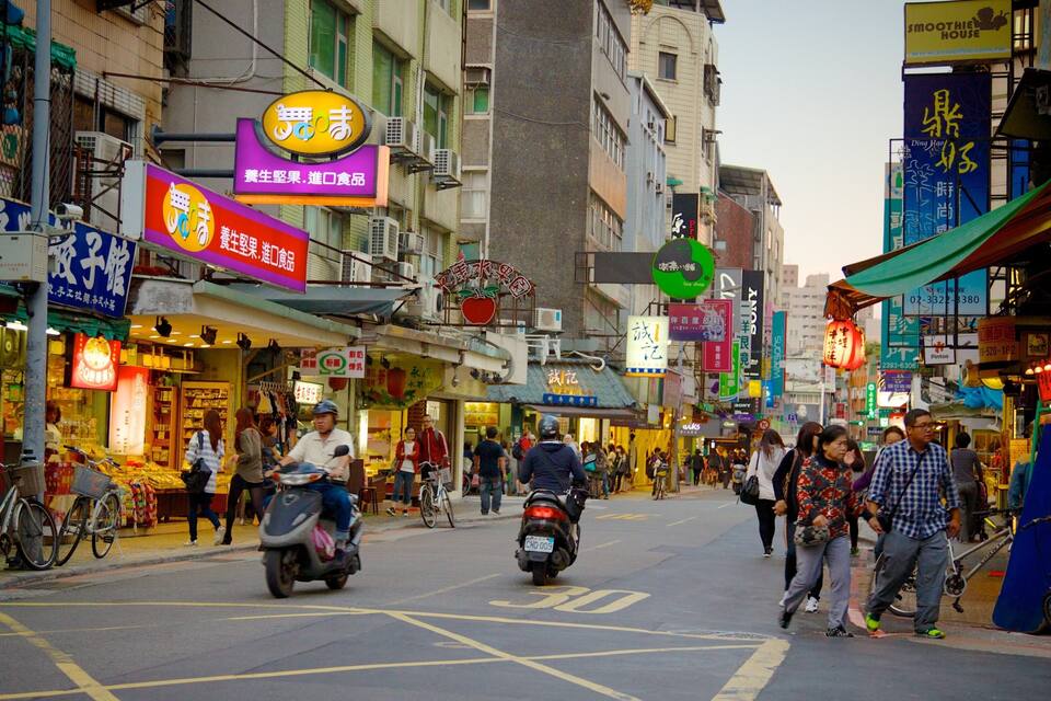 A busy street with various shops and signs, including a tea shop and a smoothie house.