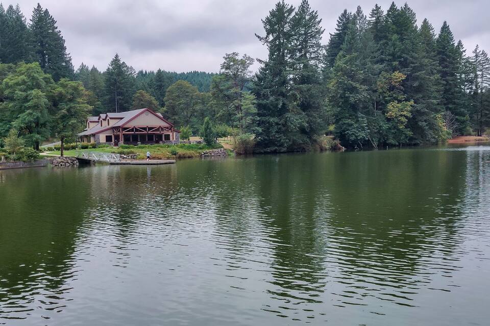 Un lago con un muelle de madera y un edificio de techo rojo.