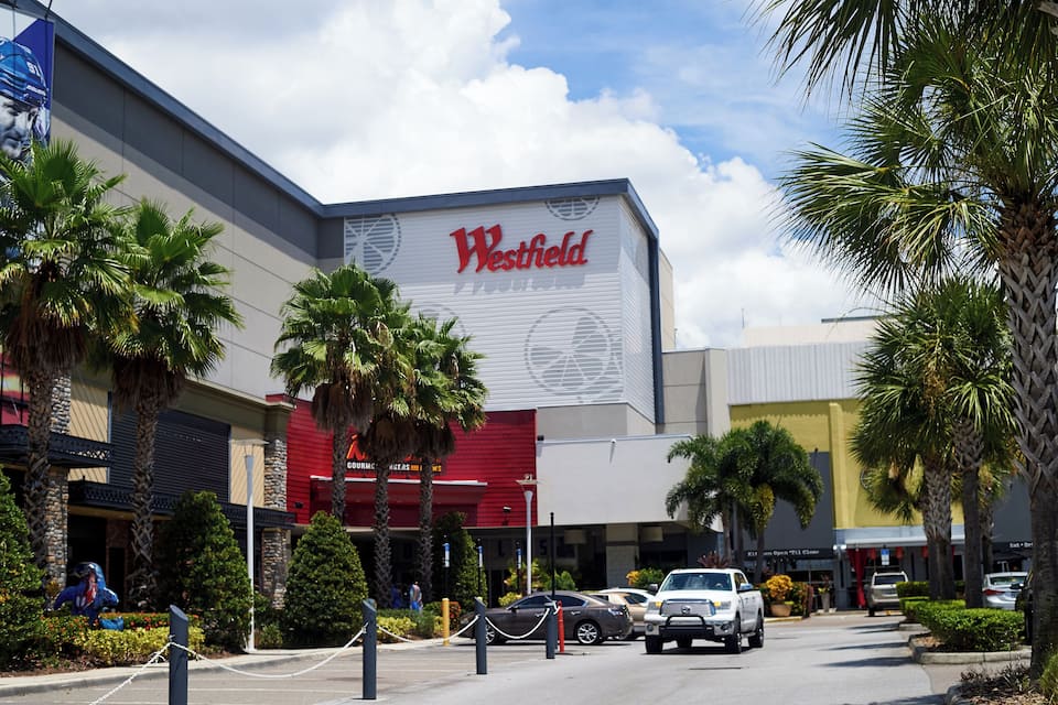 Um shopping Westfield com palmeiras e carros estacionados.