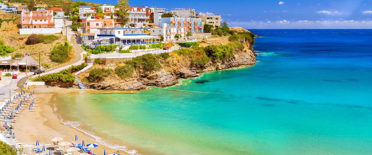 A coastal town with colorful buildings, a sandy beach, and turquoise waters.