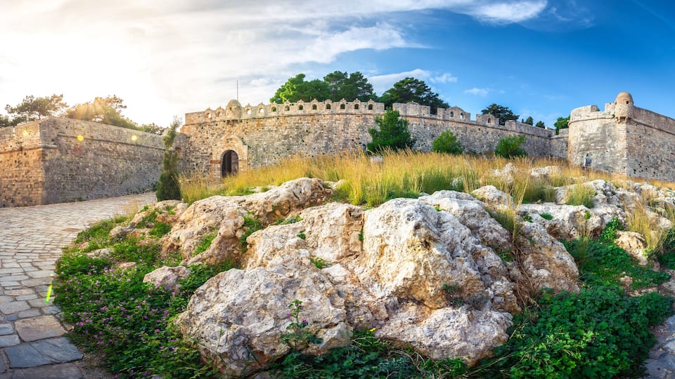 A historic stone fortress with a cobblestone pathway and lush greenery.
