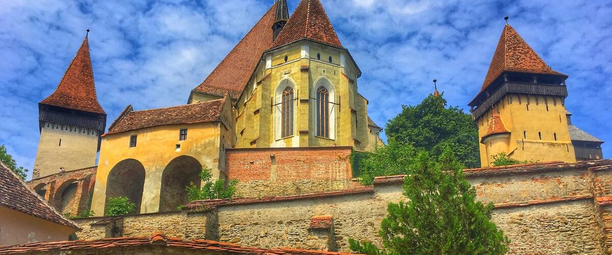 A historic building with multiple towers and a stone wall.