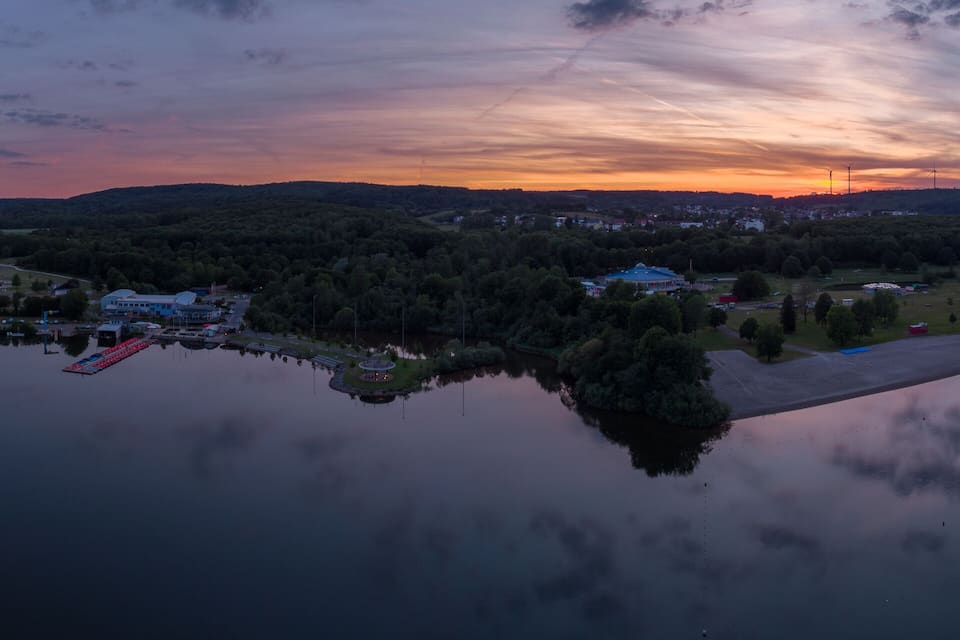 A lakeside village at sunset with wind turbines in the distance.