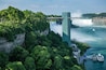 Una cascata che scende da una scogliera, un ponte e una barca ormeggiata vicino all'acqua.