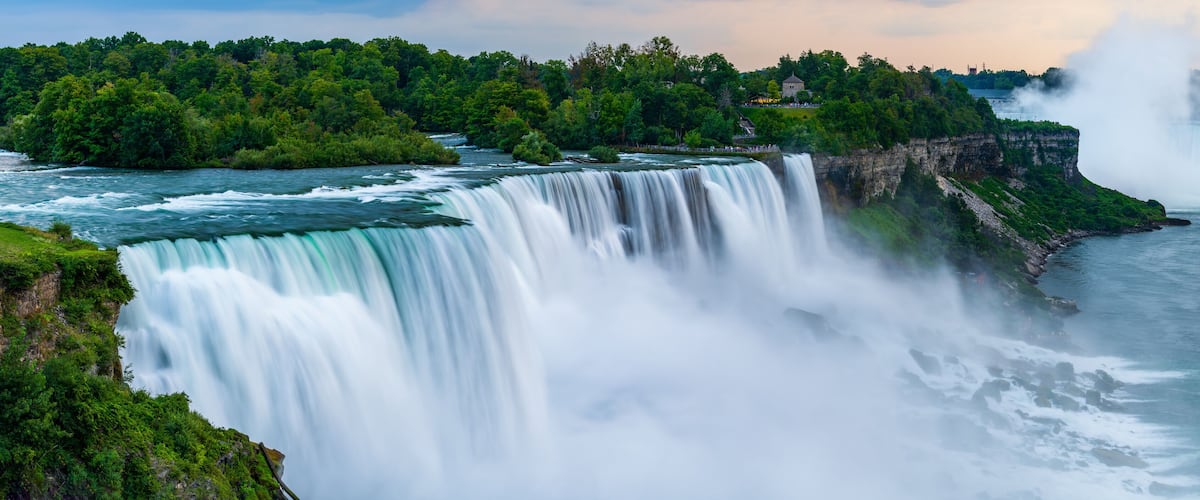 A panoramic long exposure photo of the American - Canadian waterfalls Niagara Falls in dusk.